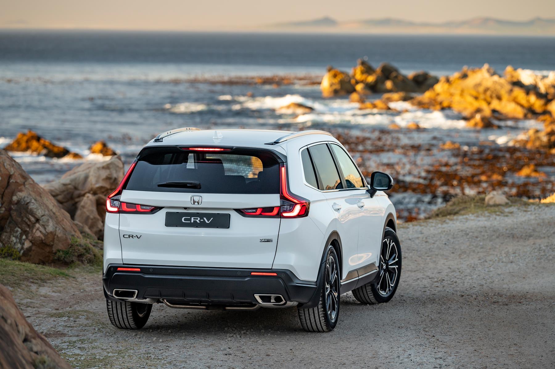 Rear view of a white Honda CR-V on a rocky beach