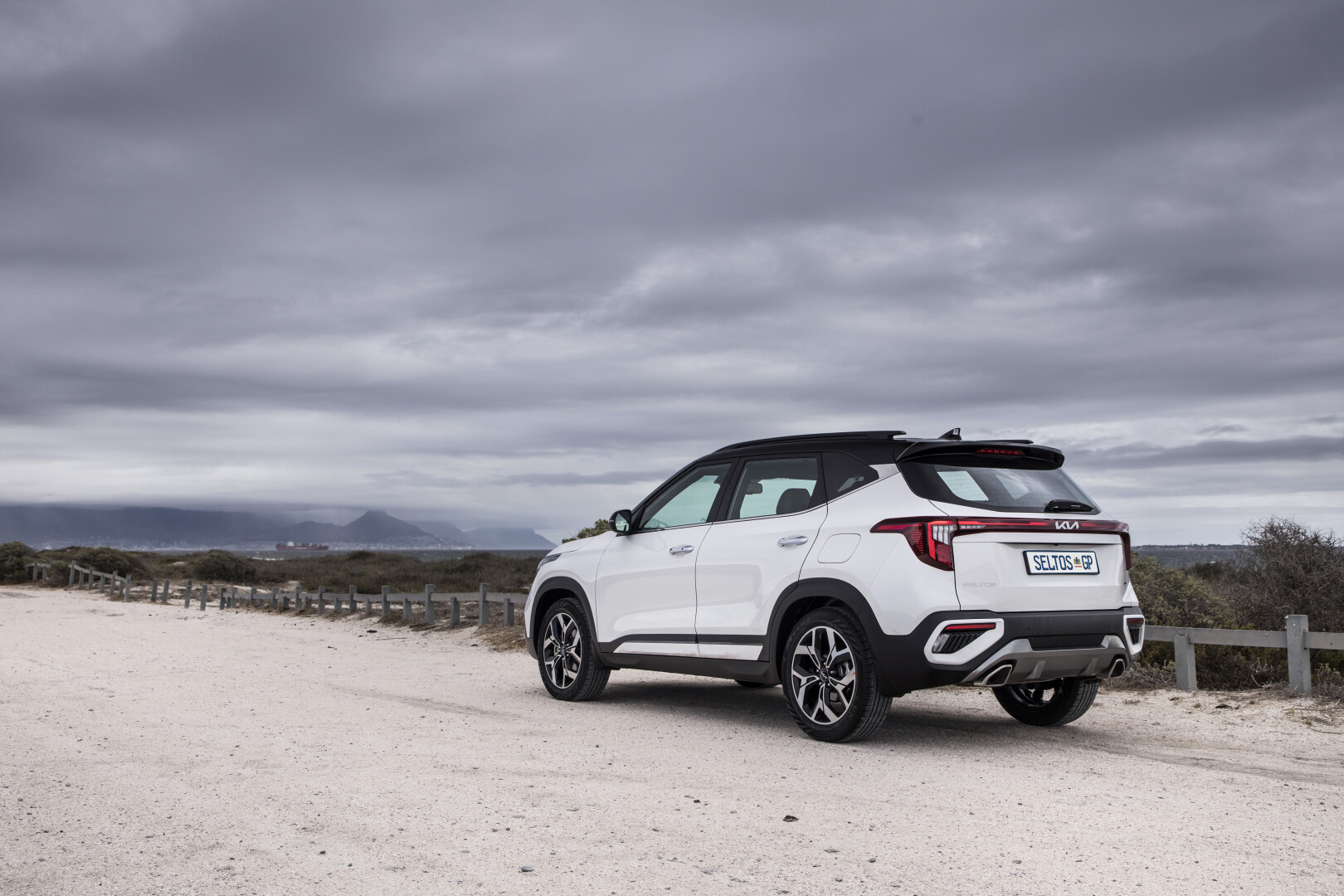 A white Kia Seltos driving on a sandy beach road in Cape Town