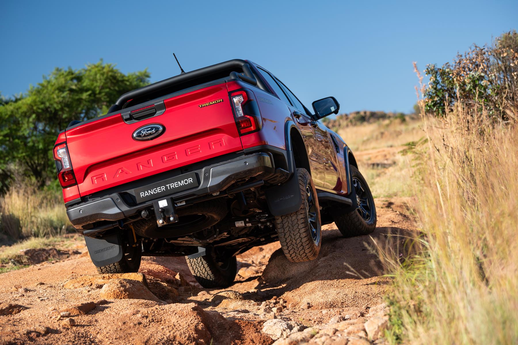 Rear view of a red Ford Ranger Tremor driving over rocks in the bush