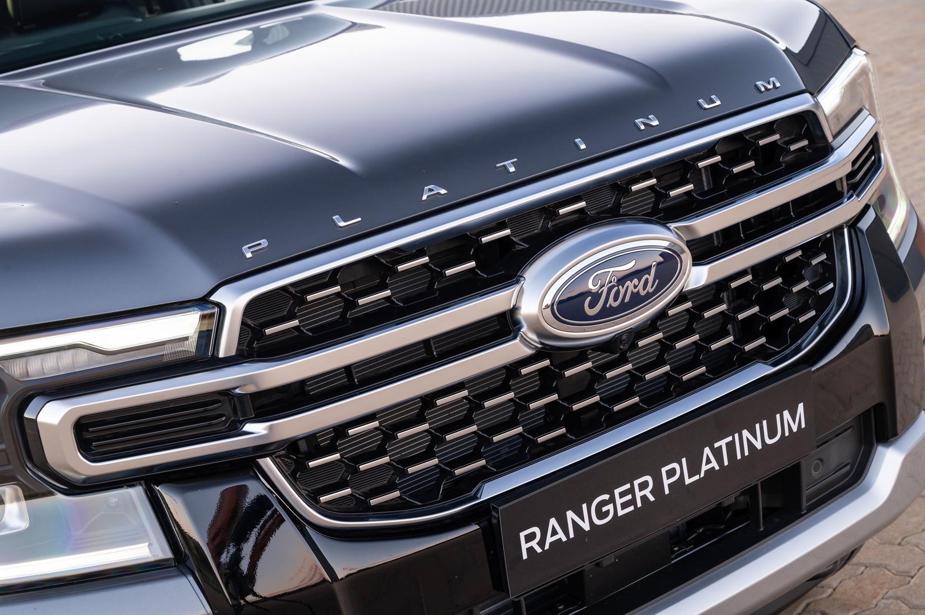 The grill of a grey Ford Ranger Platinum shoing a zoomed in view of the FORD badge and grill