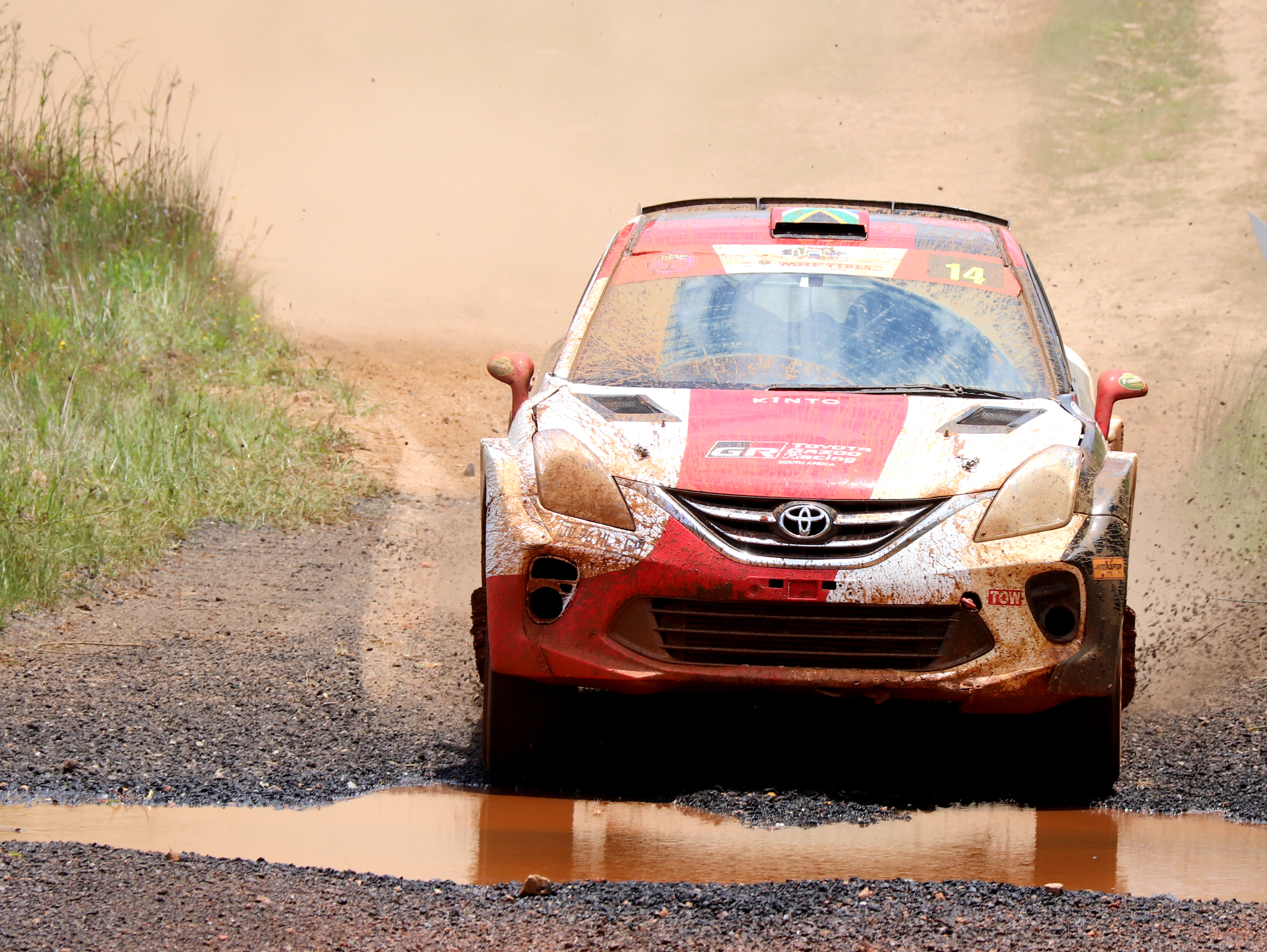 The Toyota Starlet racing through a mud pool on a rally track full of mud